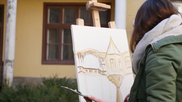 Jóvenes artistas dibujan en la ciudad. Artistas pintando cuadros en la calle. Los estudiantes pintan la construcción de la vieja ciudad europea — Vídeos de Stock