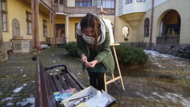 Молодий художник стискає фарбу на палітрі — стокове відео