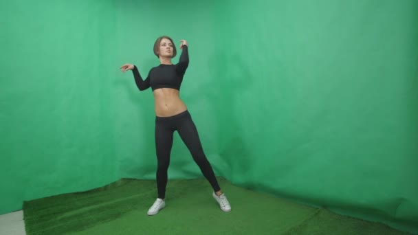 Сексуальная девушка делает элемент в танце на шесте на зеленом фоне — стоковое видео