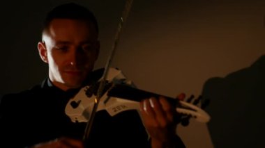 Kemancı adam siyah bir arka planda keman çalıyor. Yakın çekim