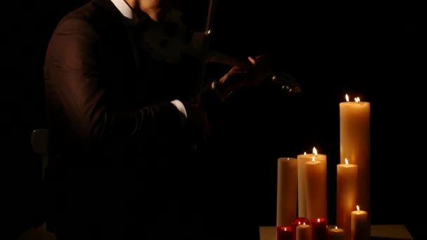 Close-up van viool speler te spelen de intstrument op zwarte achtergrond met kaarsen — Stockvideo