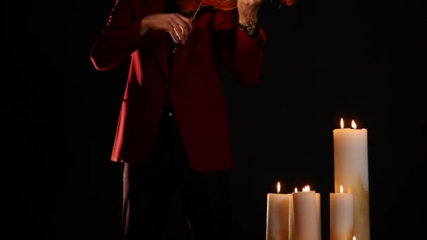 Violoniste jouant de l'intstrument sur fond noir avec des bougies — Video