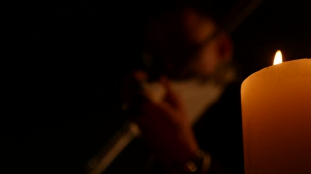 Geiger spielt das Instrument auf schwarzem Hintergrund mit Kerzen. Selektiver Fokus — Stockvideo
