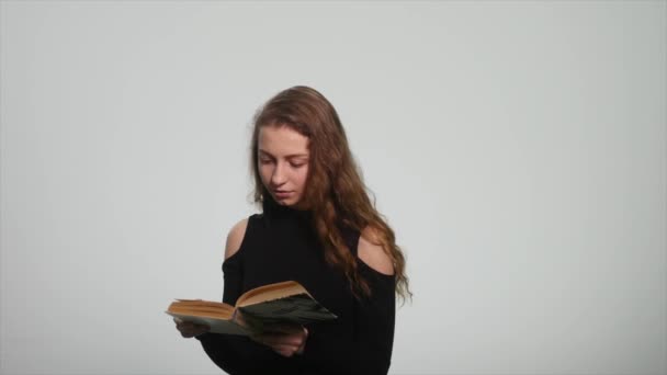 Menina bonito ler um livro sobre fundo branco — Vídeo de Stock