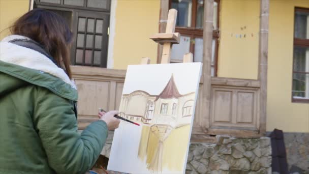 Giovani artisti disegnano in città. Artisti che dipingono quadri per strada. Gli studenti dipingono la costruzione della vecchia città europea — Video Stock