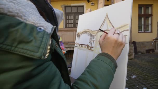 Meisje kunstenaar hand schilderij in oude straat — Stockvideo