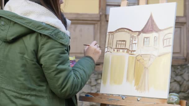 Jóvenes artistas dibujan en la ciudad. Artistas pintando cuadros en la calle. Los estudiantes pintan la construcción de la vieja ciudad europea — Vídeos de Stock