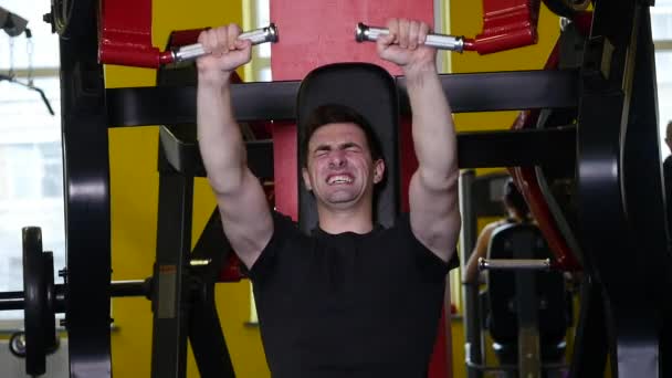 Mannen med en sport figur gör övning på simulatorn i gymmet — Stockvideo