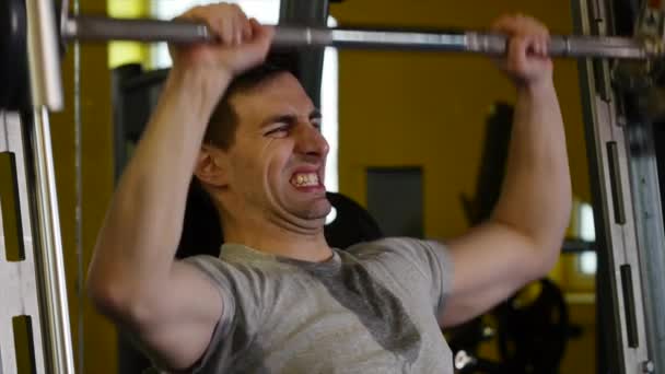 Mannen med en sport figur gör övning på simulatorn i gymmet — Stockvideo