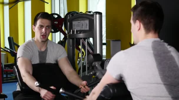 Мужчина со спортивной фигурой делает упражнения на тренажере в спортзале — стоковое видео