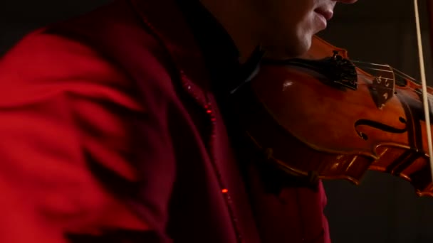 Um jovem de fato vermelho toca violino num fundo preto. — Vídeo de Stock