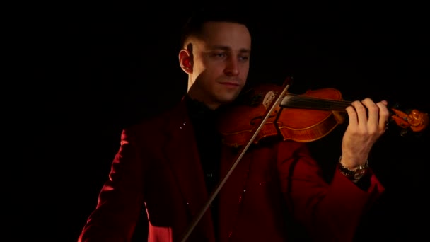 Um jovem de fato vermelho toca violino num fundo preto. — Vídeo de Stock