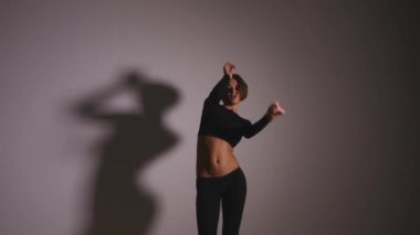 Genç ince seksi sarışın kutup dans kadın stüdyoda egzersiz. . Çekici seksi kadın direk dansör karşı gri arka plan işlemi yapıyor