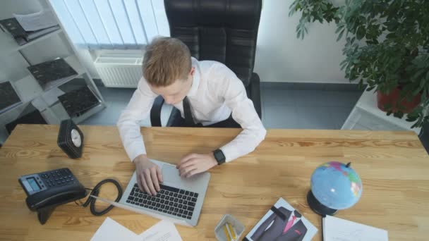 Jeune homme d'affaires travaillant sur ordinateur portable dans le bureau, vue du dessus de la table — Video