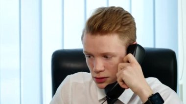 Konuşan genç adam ofiste oturan bir takım elbise. Office kavram olarak çalışıyorum. yakın çekim