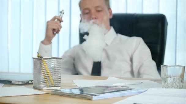 Affärsman är rökning elektronisk cigarett på arbetsplatsen i Office. slowmotion. selektivt fokus — Stockvideo