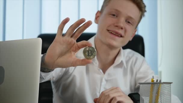 Mann mit goldenem Bitcoin bei der Arbeit mit Laptop. Fokus auf Bitcoin — Stockvideo