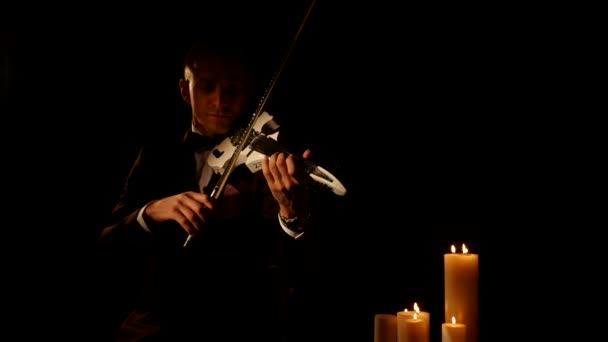 Violino tocando o instrumento em fundo preto com velas — Vídeo de Stock