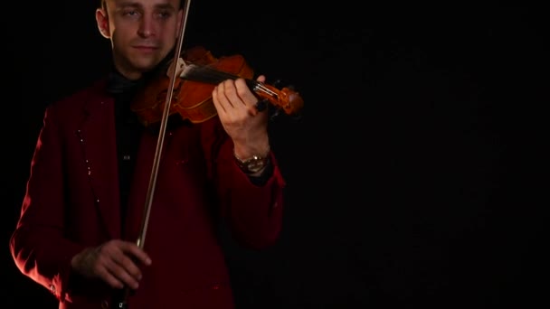 Un jeune homme en costume rouge joue du violon sur fond noir — Video