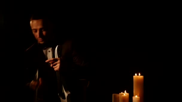Скрипач играет на черном фоне при свечах — стоковое видео