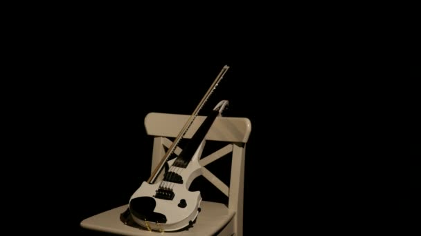 White violin on a white chair on a black background — Stock Video