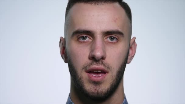 Wütender junger Mann auf weißem Hintergrund. Nahaufnahme — Stockvideo