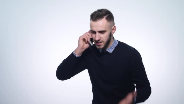 Сердитий молодий чоловік говорить на своєму мобільному телефоні. ізольовані на білому. Молодий чоловік розмовляє мобільним телефоном — стокове відео