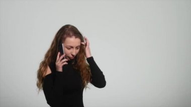 kızgın genç kadın beyaz bir arka plan üzerinde onu cep telefonuyla söz