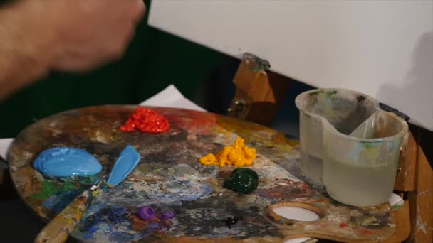 Die Hände des Künstlers, indem er Farbe aus der Tube auf die Palette drückt. Nahaufnahme — Stockvideo