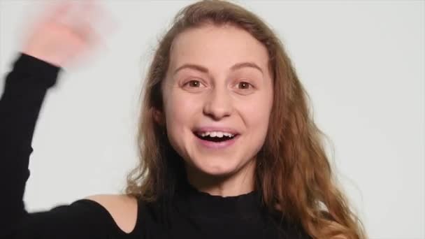 Atractiva joven rubia agitando su mano en el aire con emoción y riendo — Vídeos de Stock