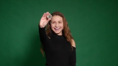 Kız bir bitcoin para elinde tutar.