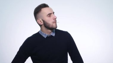 Ağzında kürdanla kameraya bakan yaratıcı, hoş, genç bir adam. Duygu kavramına çok yakın.