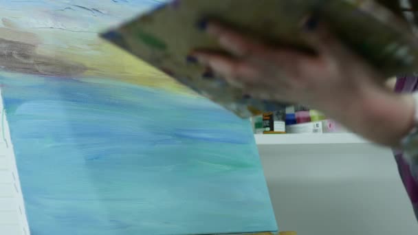 Genç bir kadın bir resim arkasında, atmosferik bir atölye bir şövale bir tuval üzerine boya — Stok video