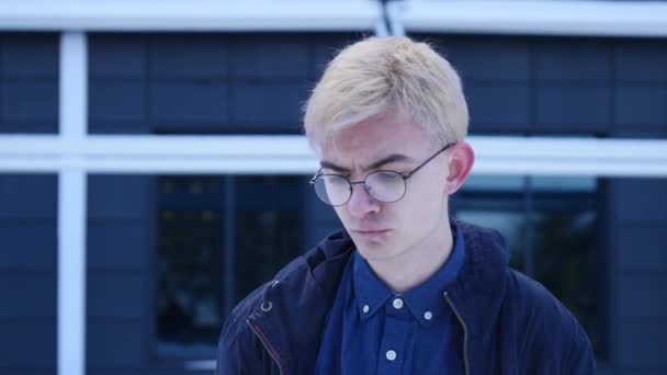 Triste joven en gafas sobre fondo gris — Vídeos de Stock