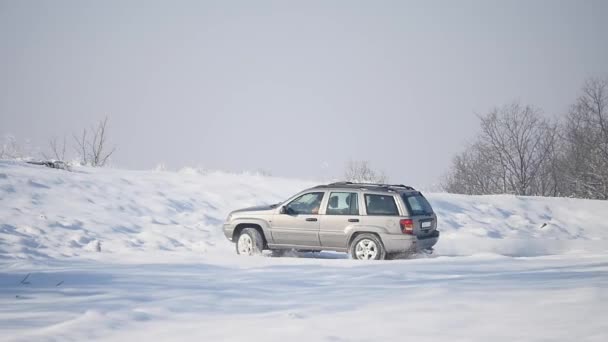 Suv con ruedas nevadas y neumáticos de invierno conduciendo sobre nieve — Vídeos de Stock