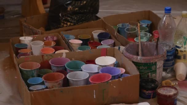 30.01.2018, Chernivtsi, Ucrania - Latas de plástico multicolores con pinturas. Fondo del lugar de trabajo artista. Antiguo fondo Pinturas sucias. Colorida paleta de artistas. Tono suave. Creatividad, concepto de arte visual — Vídeo de stock