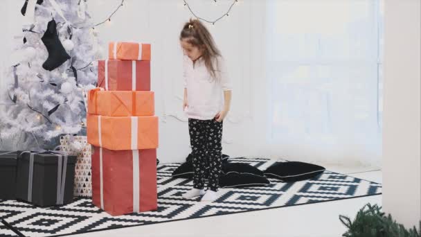 Criança bonito preparou uma pilha de caixas de presente vermelho com fitas brancas para seus amigos e familiares, contou-os e adormecer . — Vídeo de Stock