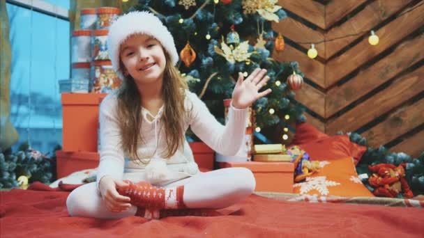 Zeitlupe 4k Video von lustigen Mädchen mit rotem Hut, die Hand schwenken und alle anlässlich des bevorstehenden Neujahrs grüßen. Frohe Weihnachten und ein gutes neues Jahr. — Stockvideo