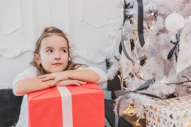 Dikkatsiz, gülümseyen küçük bir bayan Noel zamanının ve hediyelerinin tadını çıkarıyor..