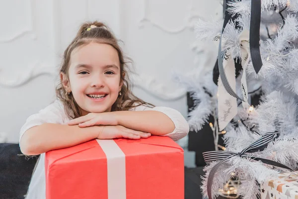 Leichtsinniges, lächelndes kleines Weibchen genießt Weihnachtszeit und Geschenke. — Stockfoto