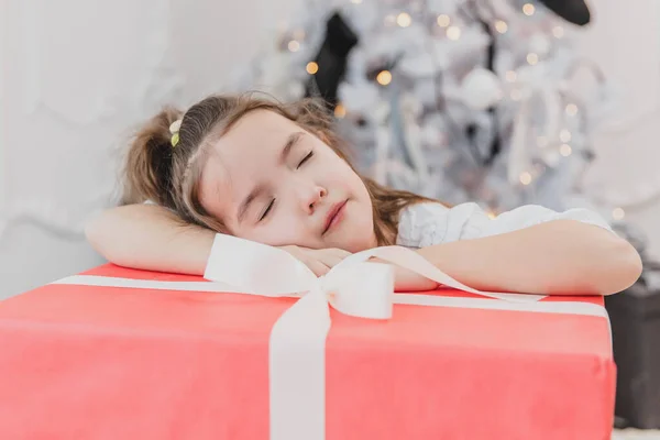 Gros plan photo de fille douce avec queue de cheval dort sur un grand cadeau de Noël, à la recherche incroyable . — Photo