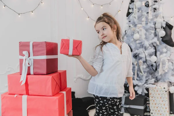 Hermosa niña jugando con cajas de regalos de Navidad, construyendo una pirámide . — Foto de Stock