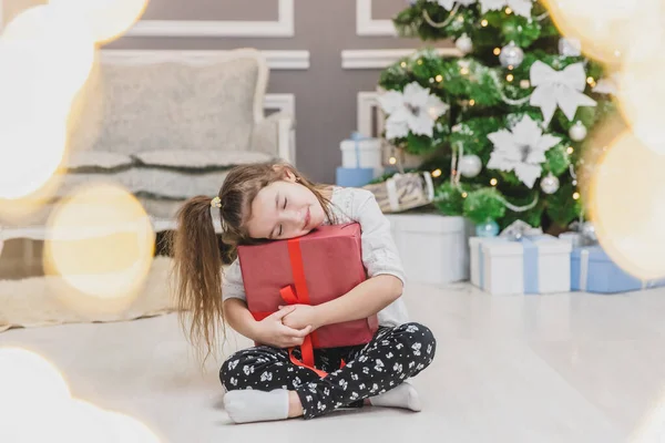Douce fille avec queue de cheval dort sur le grand cadeau de Noël, à la recherche incroyable . — Photo