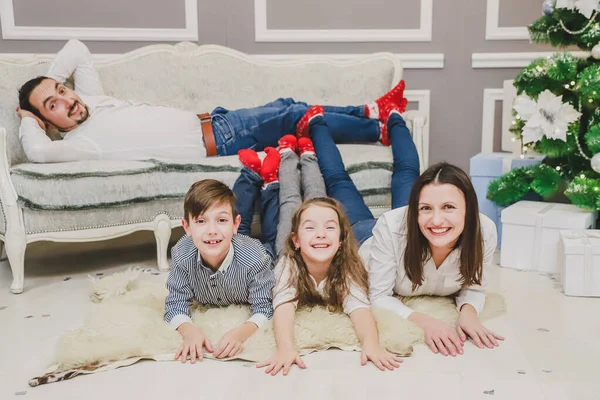 Linda familia jugando en la mañana de Navidad, divertida madre padre e hijos en calcetines rojos en ambiente de vacaciones . —  Fotos de Stock