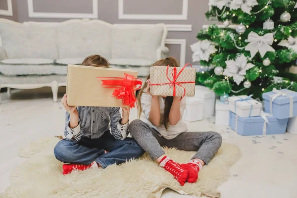 Nieostrożna siostra i brat cieszą się świętami Bożego Narodzenia, chowając twarze za dużymi pudłami. — Zdjęcie stockowe
