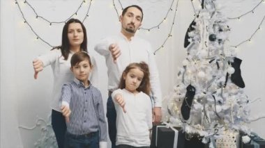 Çocukların ve ailelerinin somurtkan suratlarını gösteren yeni yıl videosu, başparmakları aşağıda olan hoşnutsuzluğu gösteren negatif işaretler.