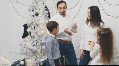 Ebeveynler ve iki kardeş noel ağacının yanında bir araya geldiler ve birbirlerine yeni yıl dileklerini, işaret parmaklarını söylediler..