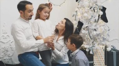 Anne, baba ve kardeş sakin olun. Beyaz Noel arka planında ağlayan küçük kız..