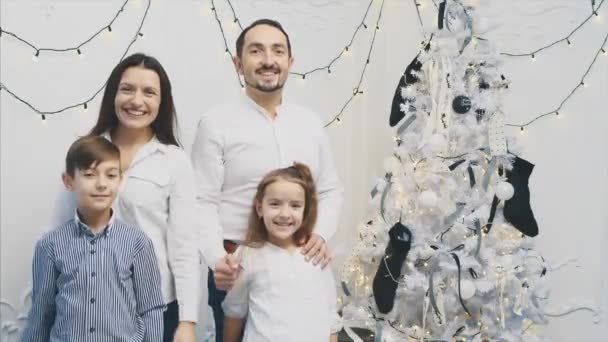 Padres cariñosos y niños pequeños de pie cerca del árbol de Navidad, posando y dando pulgares hacia arriba . — Vídeos de Stock