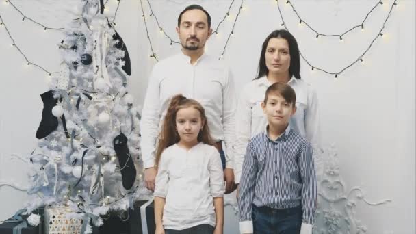 Непонятное настроение родителей и детей, стоящих расстроенных возле рождественской елки, в то время как Рождество это время, чтобы улыбаться и праздновать . — стоковое видео